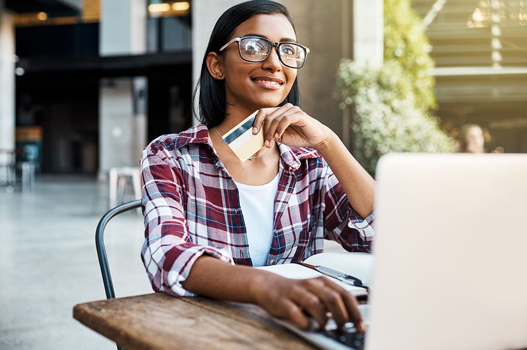 Woman outside about to pay for something on her laptop