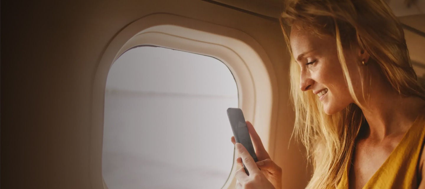 smiling woman holding phone on a plane