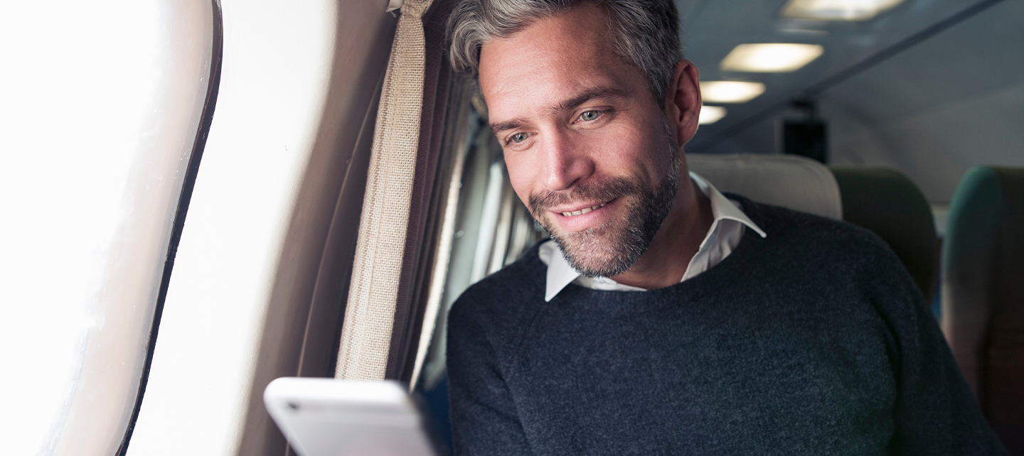 Man looking at phone in an airplane