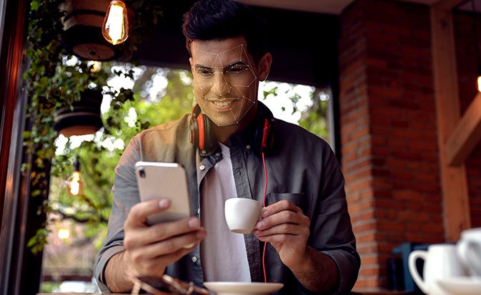 Man using smartphone with facial recognition system.