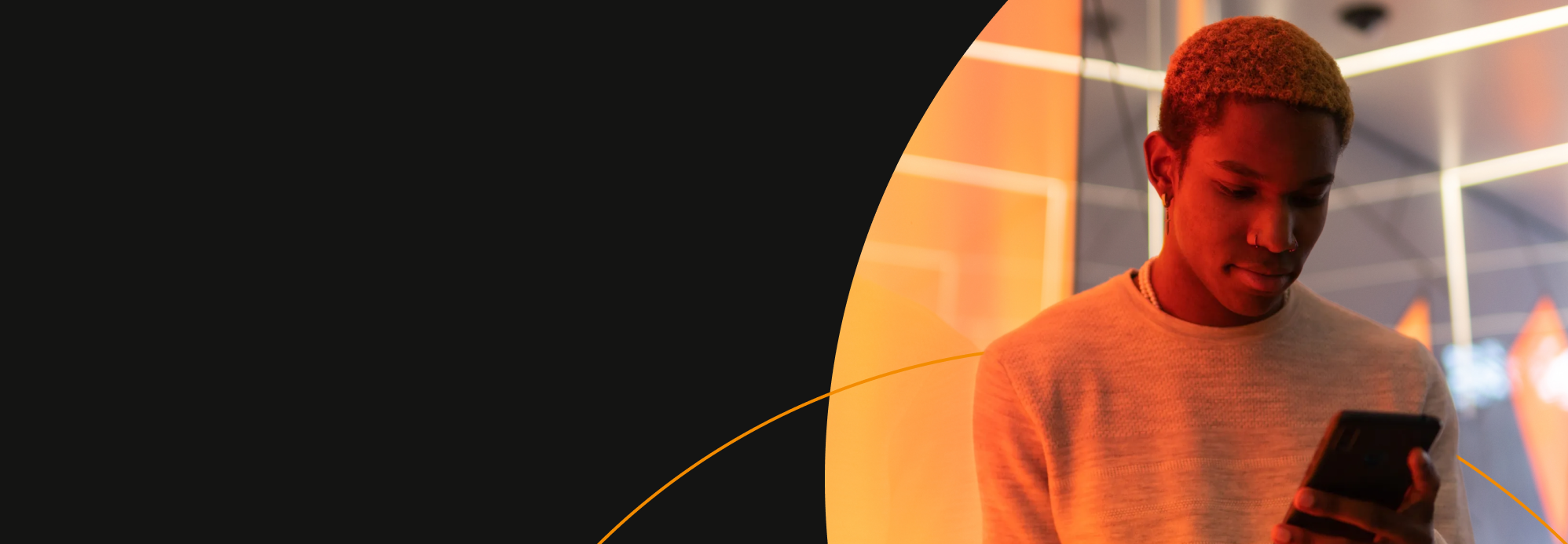 Guy looking at phone in front of orange lighting