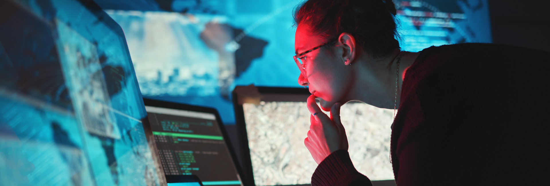 A woman looks at a computer with a digital map in the background. 