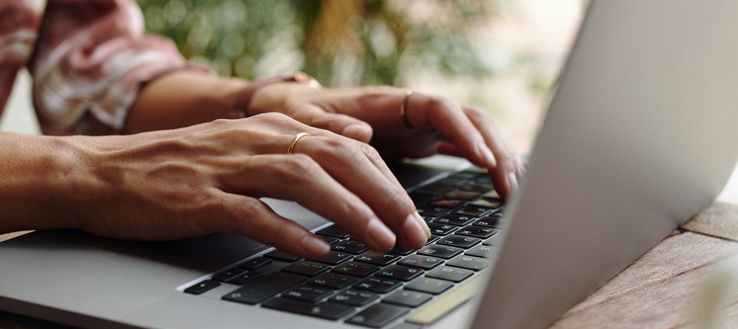 Hands typing on a laptop