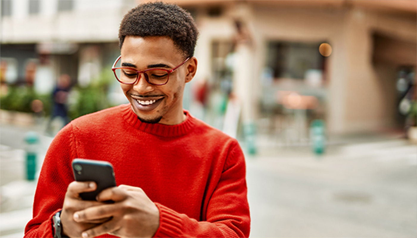 Man in a red sweater smiling at phone