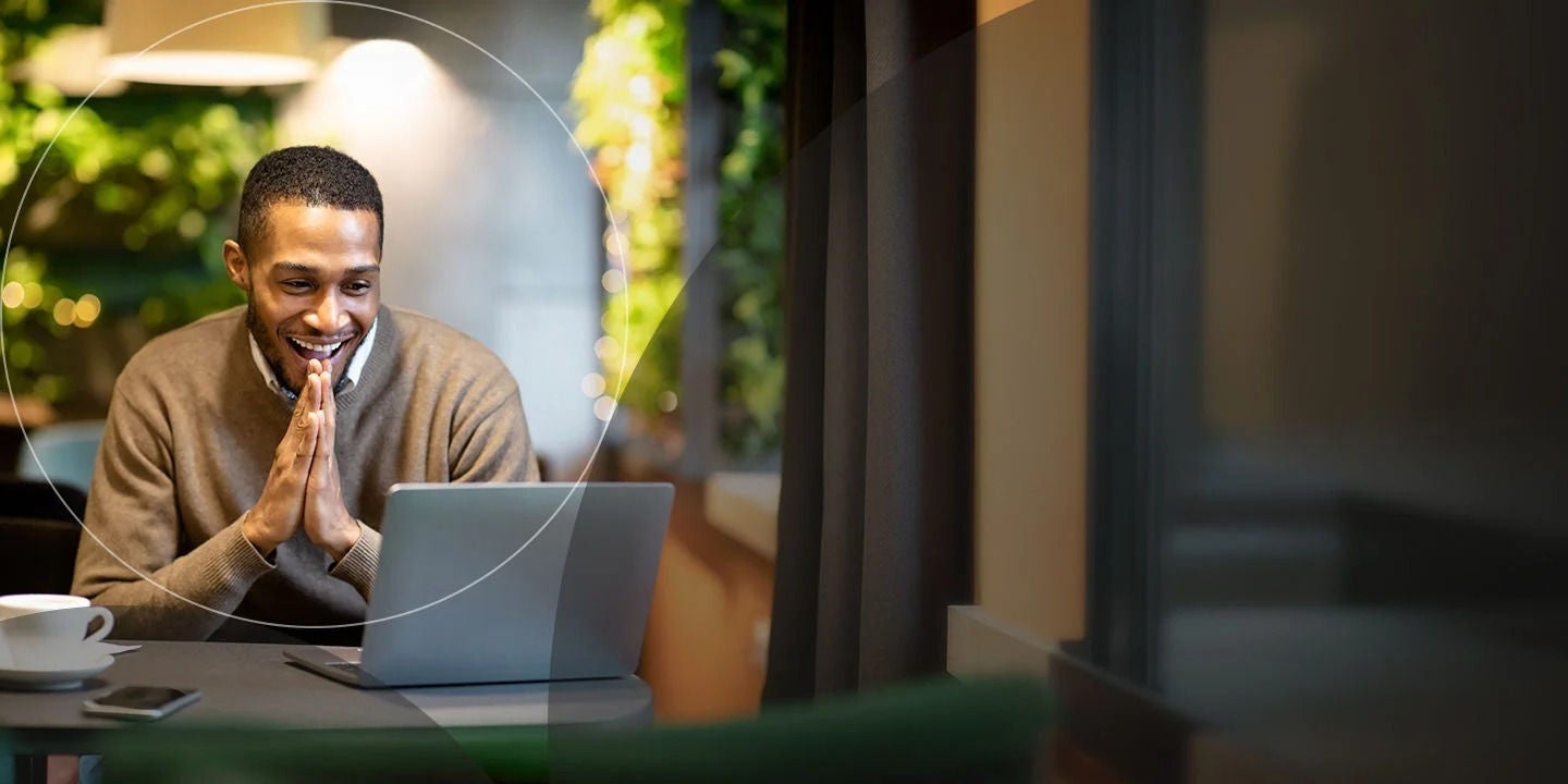 איש עסקים צעיר משתמש במחשב הנייד בזמן ישיבה בבית קפה.