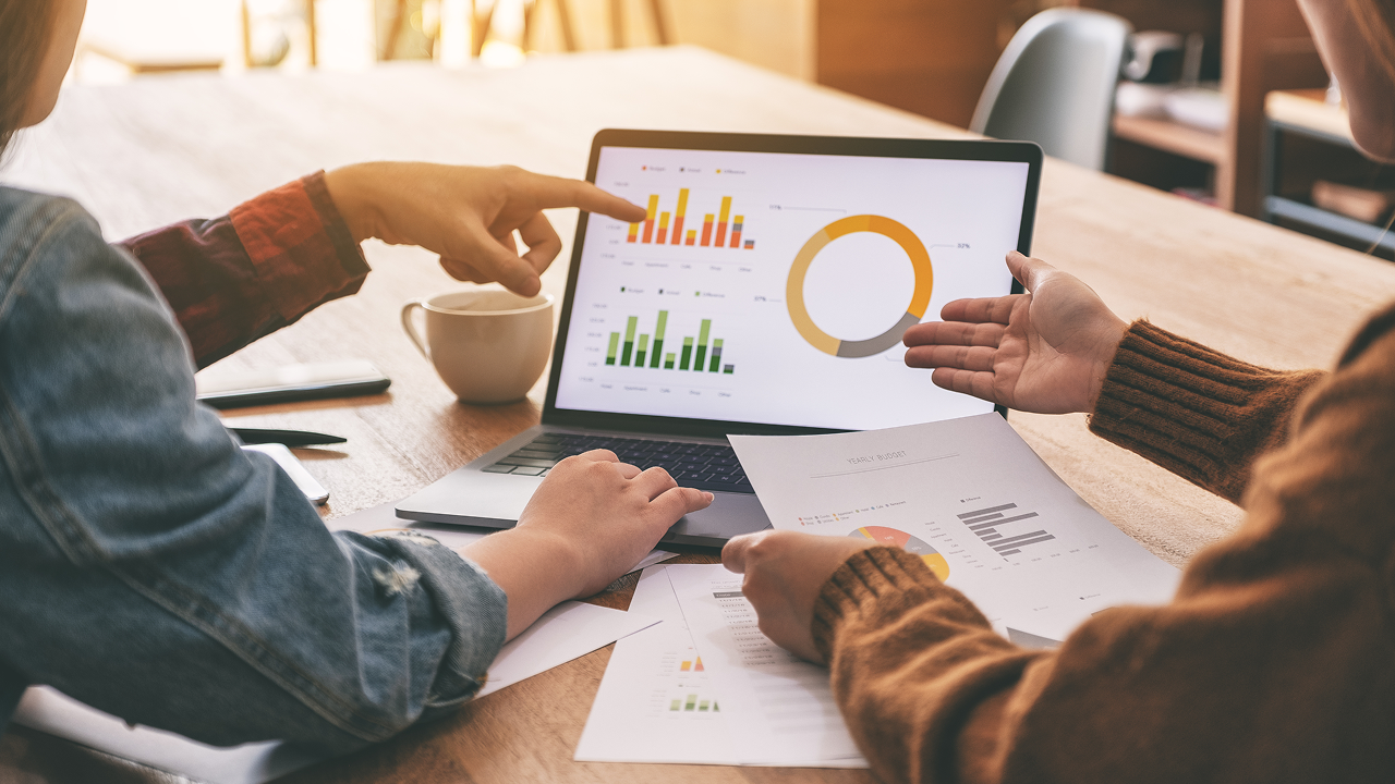 Two people pointing to a graphic on a computer