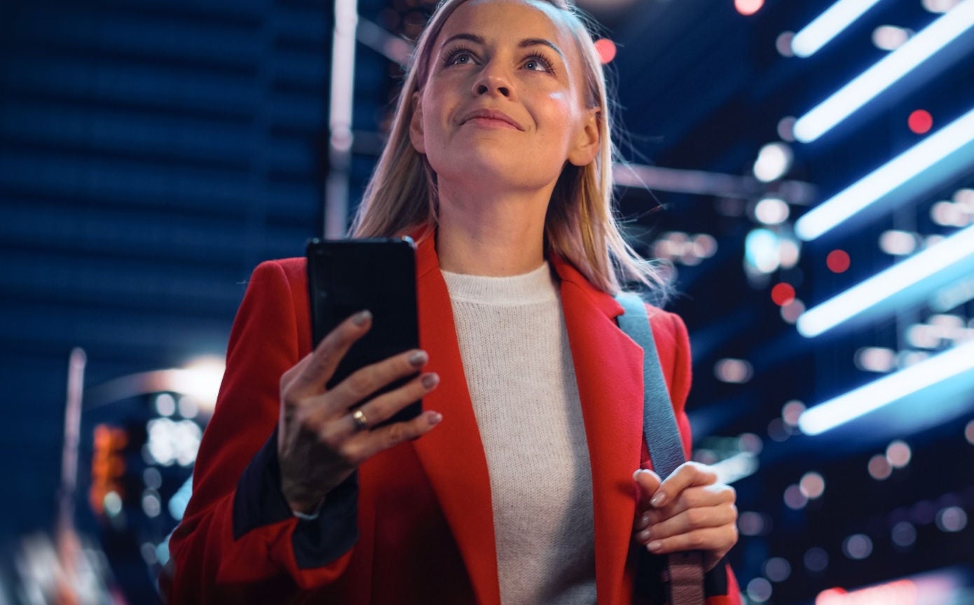 Žena koristi mobitel u noćnom izlasku.