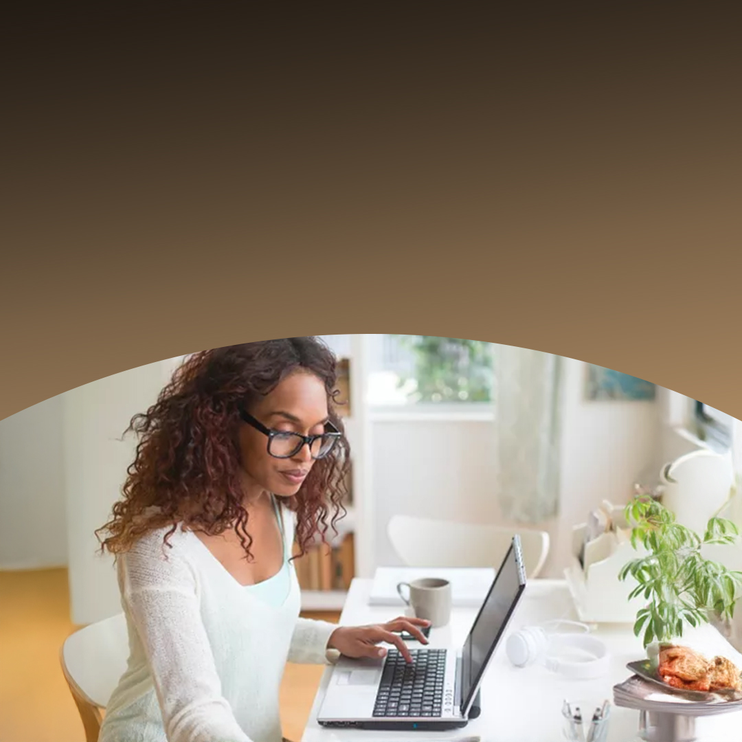 Woman working on a laptop at a bright home office.