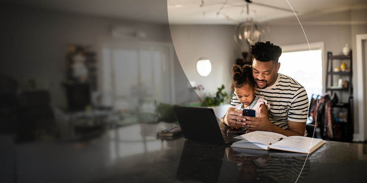 Man with child looking at phone in the kitchen.