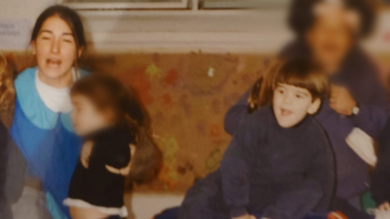 A younger Maria Laura Tabanera holds a couple of children as kindergartner Nicolas Lagreste Zucchini sits nearby in a classroom.