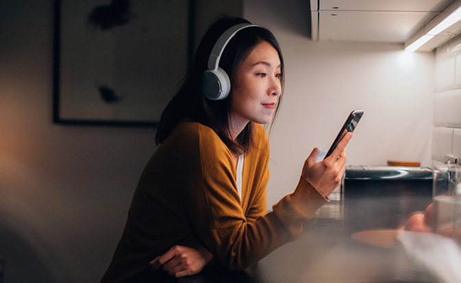 mujer con audífonos usando un teléfono.