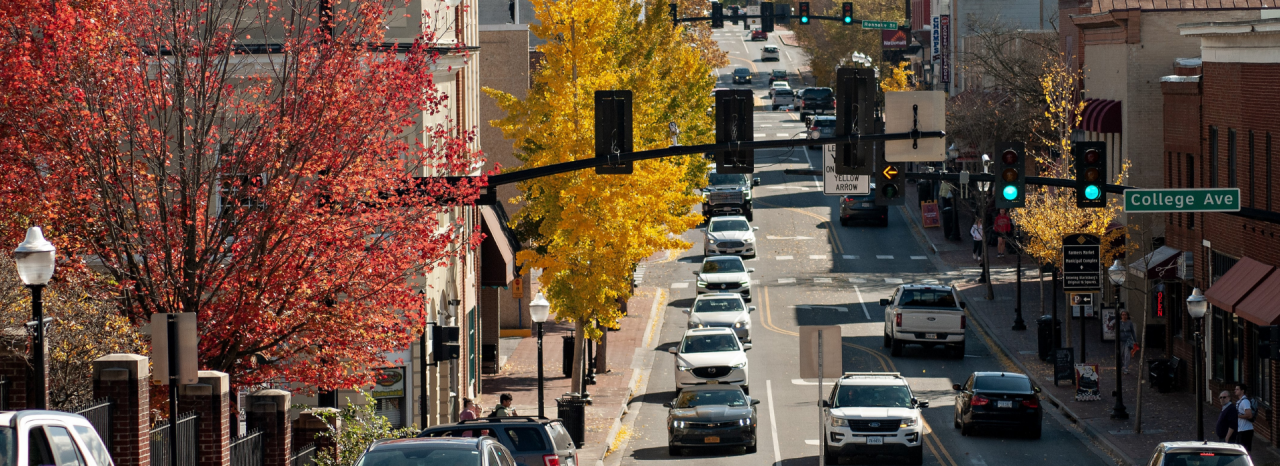 Cars on Blacksburg's main street during the fall as the trees lining the road are turning colors.