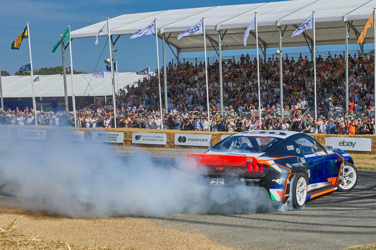 A race car billowing exhaust on the track at the Festival of Speed. 