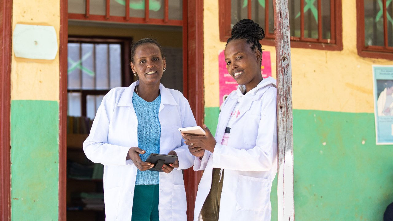 Two nurses smiling outside a clinic