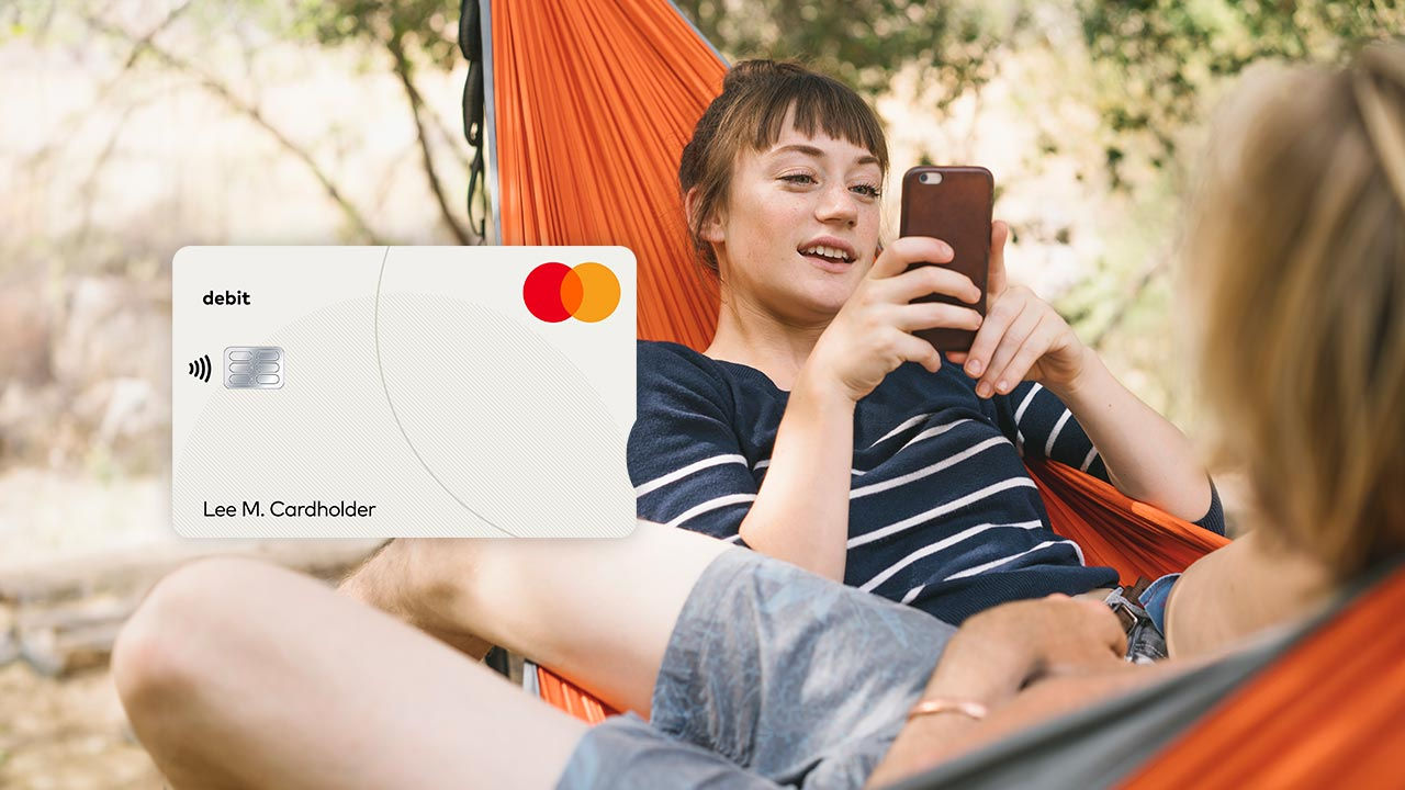 Dos amigos se relajan en una hamaca e imagen de una tarjeta de débito Mastercard.