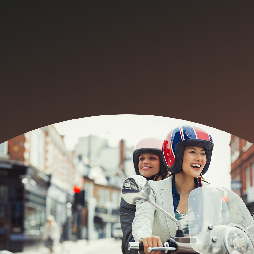 Zwei Frauen fahren Roller auf der Straße.