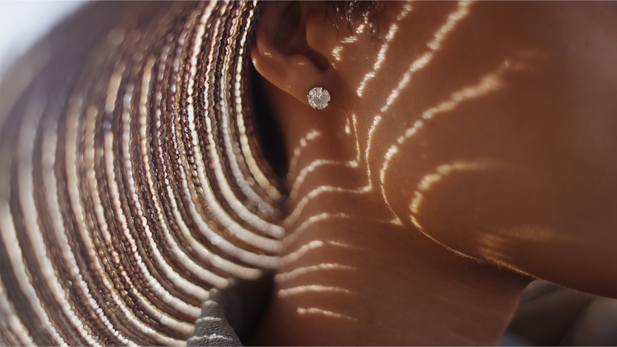 Close up of woman with sunhat and diamond earing.