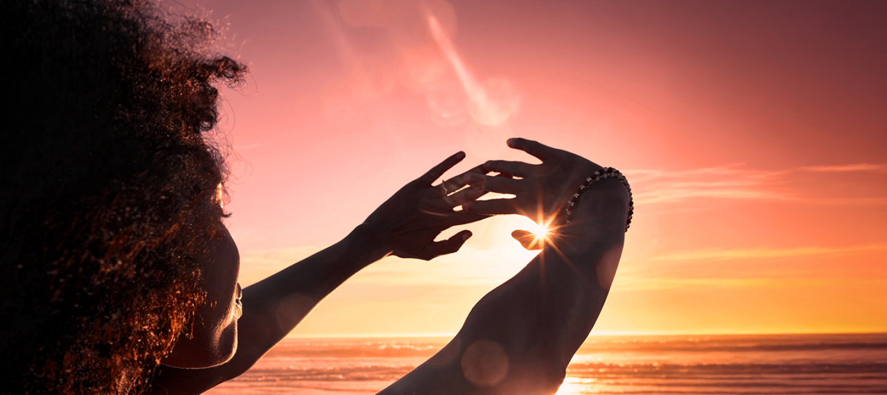 Frau, die die Sonne mit ihren Händen einrahmt