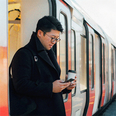 Mann schaut am Bahnhof auf sein Telefon.
