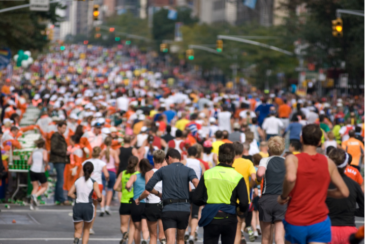 Ein Strom von Läufern in bunten Laufkleidung läuft während des NYC Marathon eine Straße in New York City entlang.