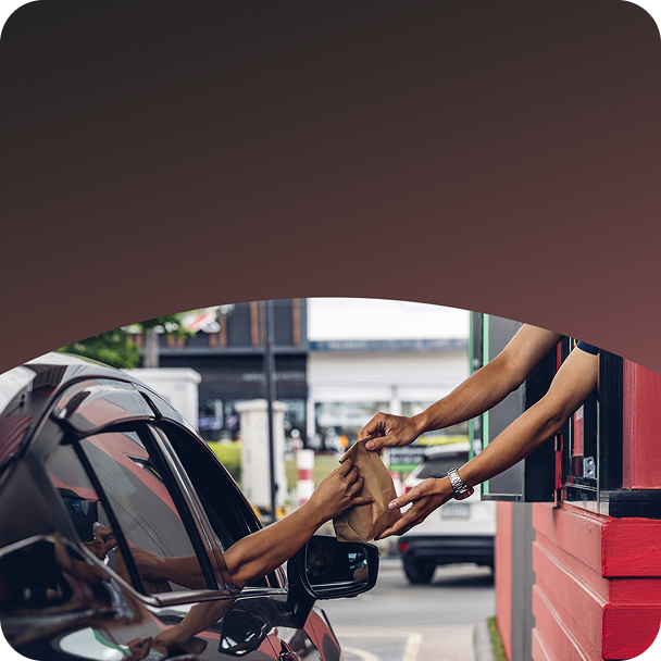 Employee handing customer food in drive thru.