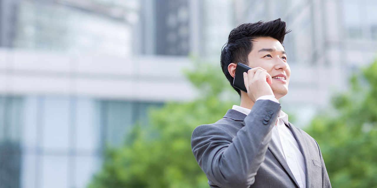 Gənc asiyalı kişi telefonundan istifadə edir.