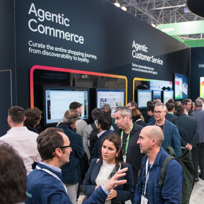 Attendees mingle in front of a busy display about agentic commerce at NRF 2026. 