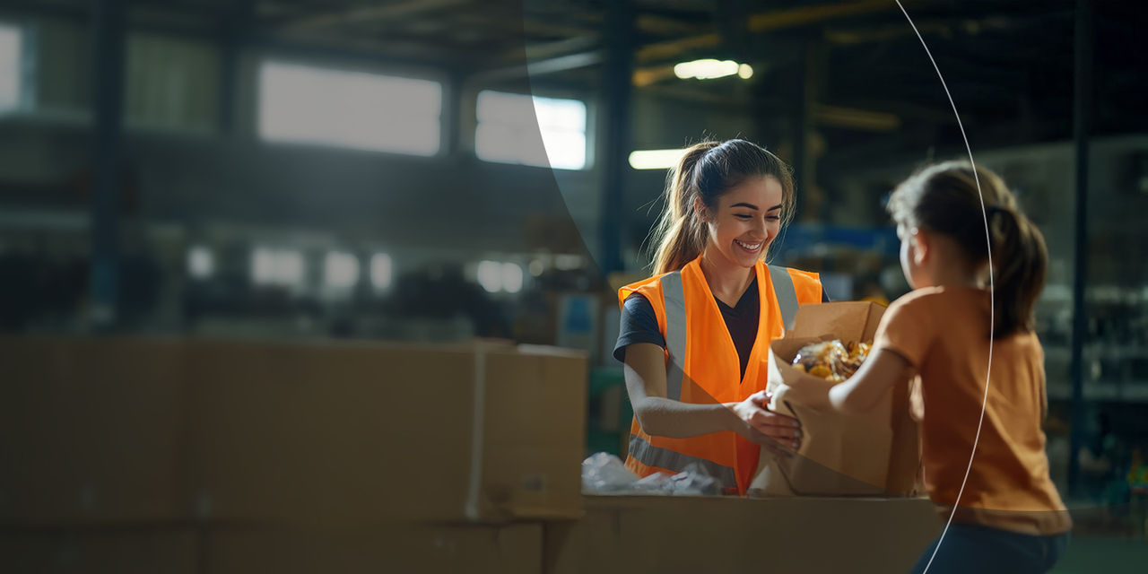 Radnik koji predaje papirnu vrećicu maloj djevojčici.