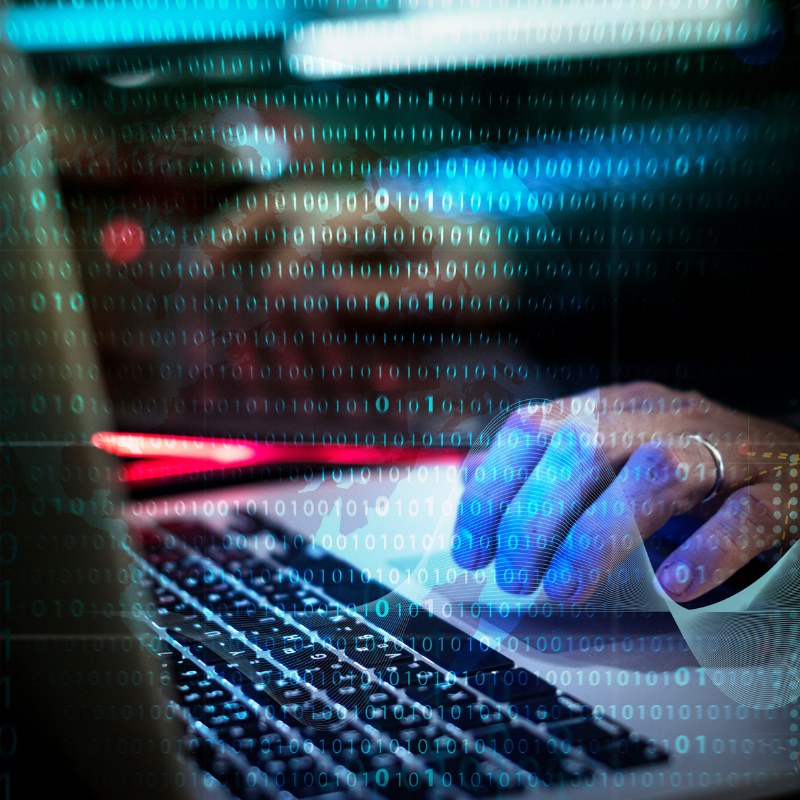 A person types at a laptop with a digital overlay . 