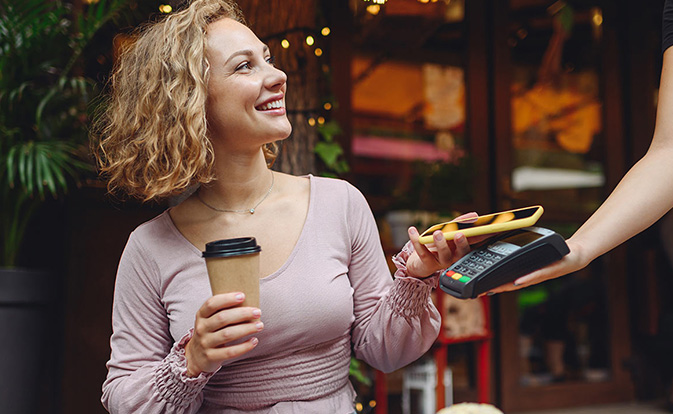Une femme paie un café avec son téléphone.
