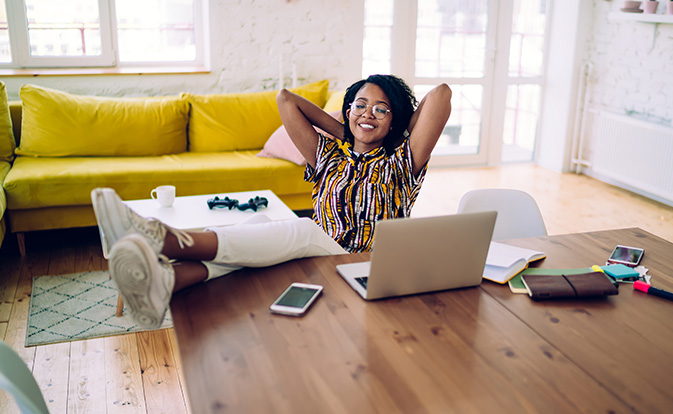 Glimlachende zwarte freelancer die uitrust na het werken op een laptop.