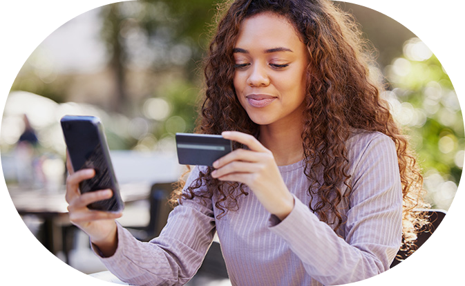 Vrouw glimlacht terwijl ze winkelt en op haar telefoon kijkt.