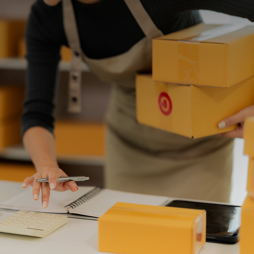 Een vrouw houdt een pen vast, klaar om op een notitieblok te schrijven in een goed verlichte kantooromgeving.
