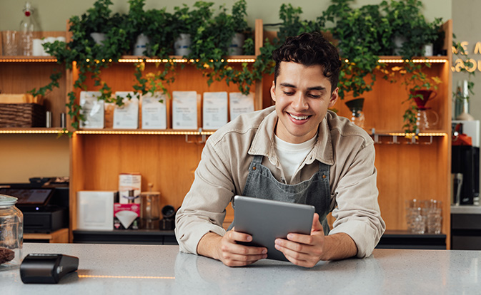 Eigenaar van koffietentje aan de balie met een digitale tablet.