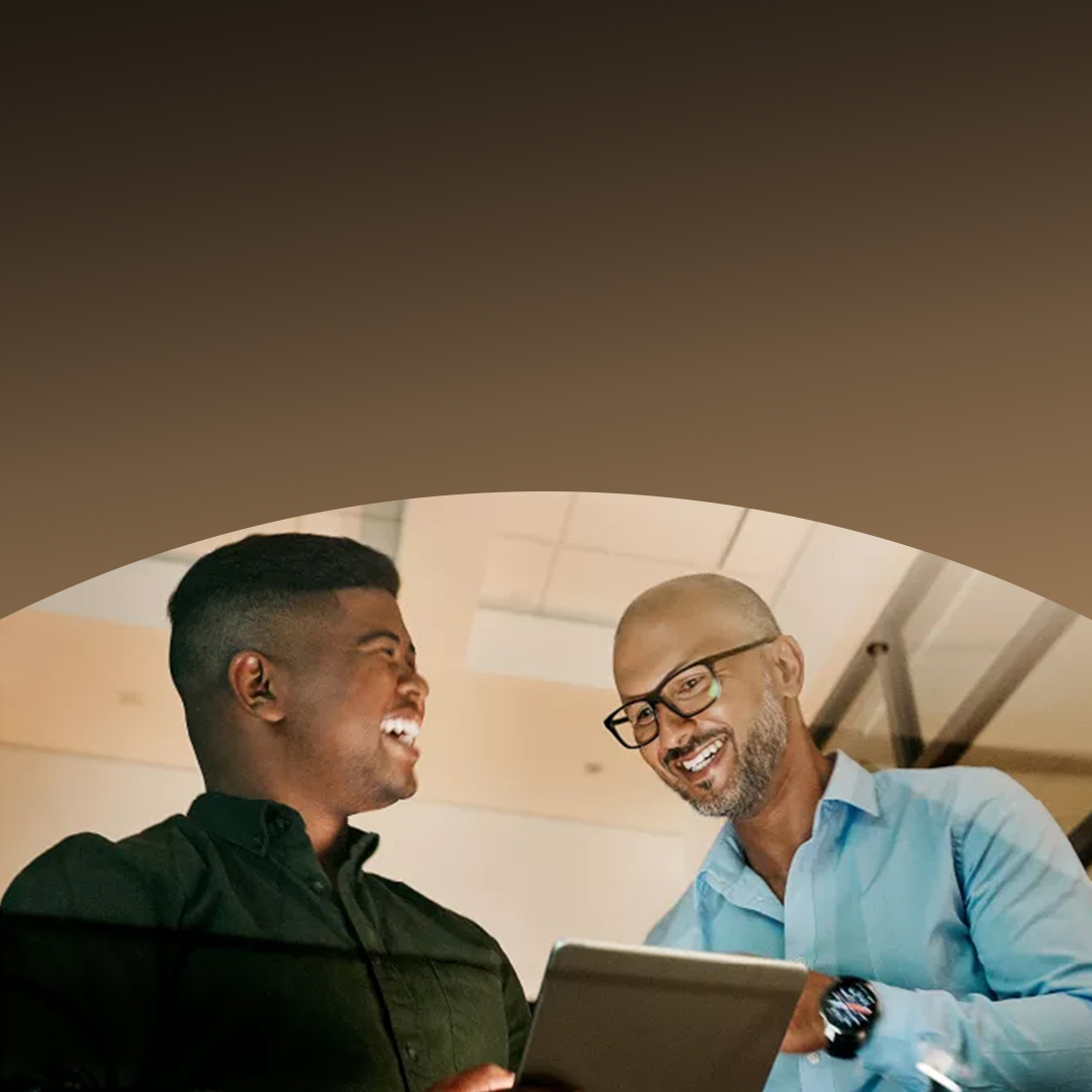 Two men laughing and looking at a screen.