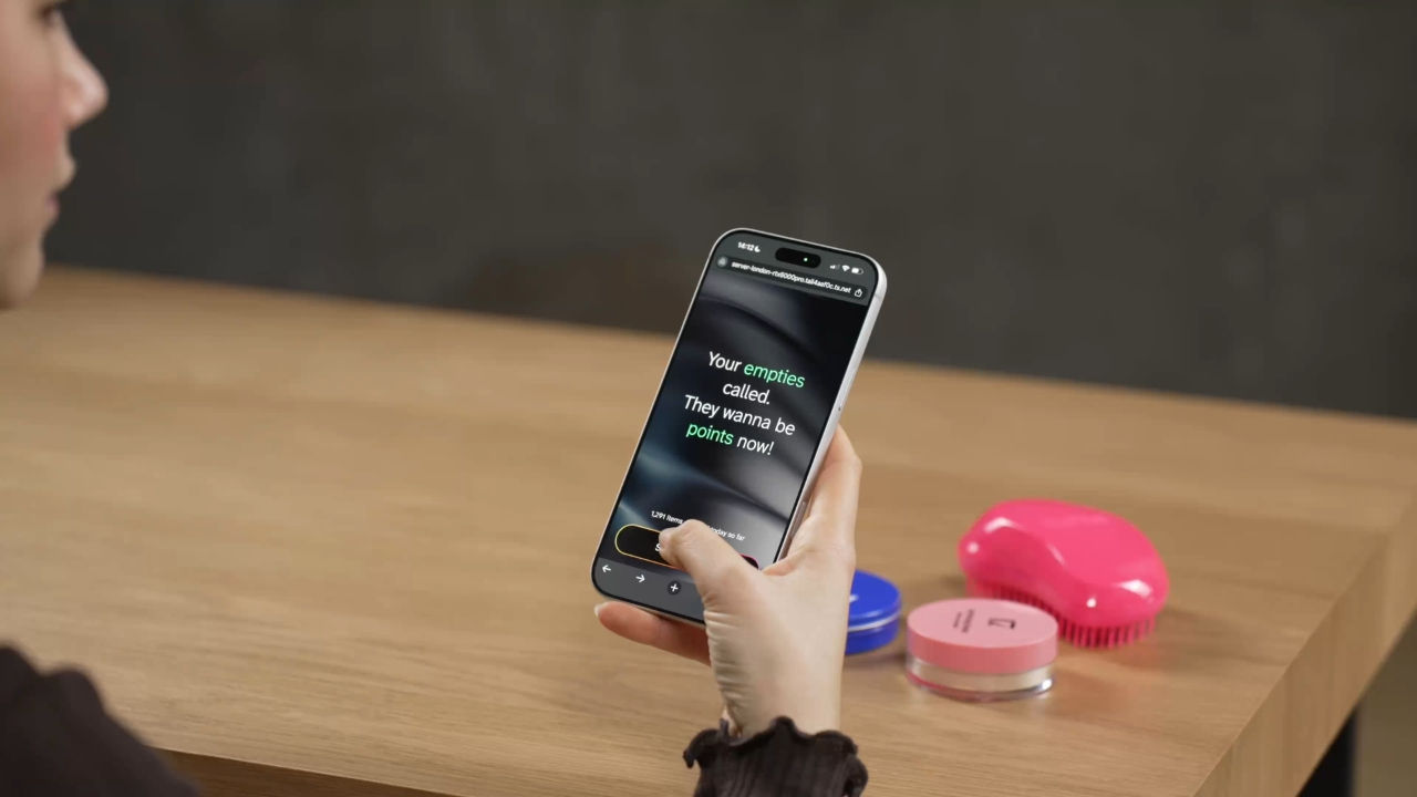 A person holds up a phone to a table with empty bottles on them. 