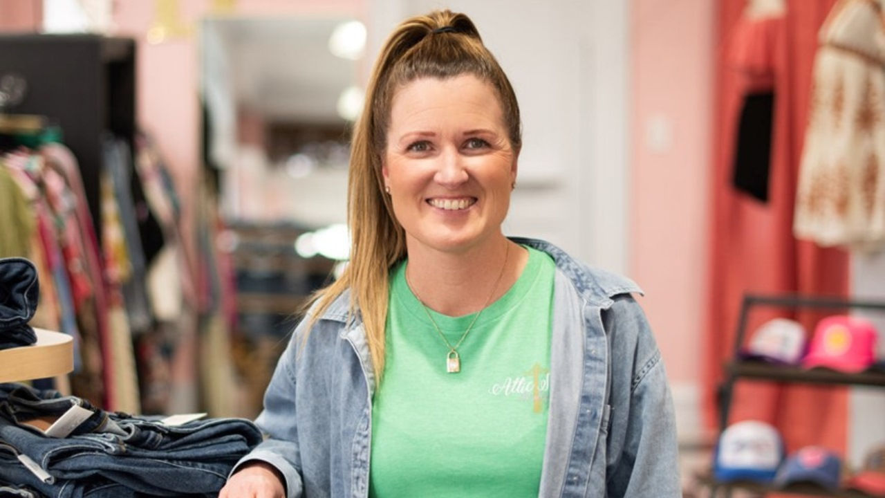Kristin Morron smiles next to a clothing display in Attic Salt. 