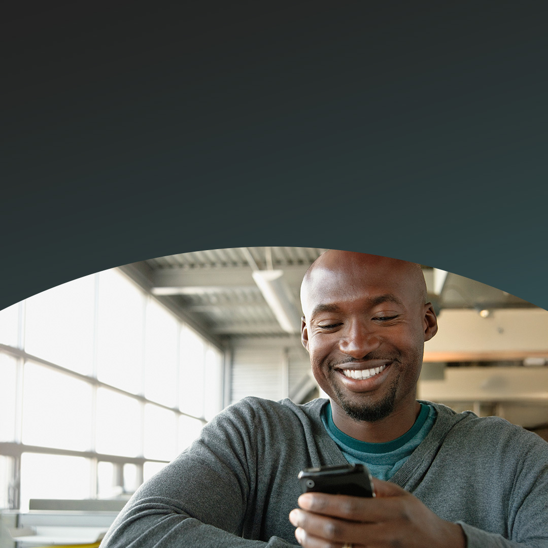 Homem no escritório olhando para o celular.