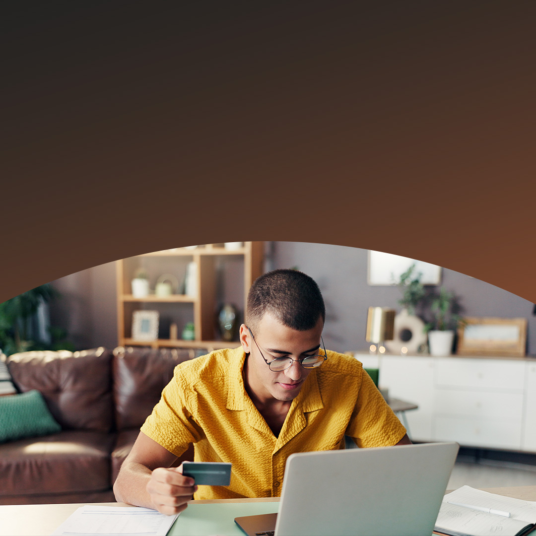 Homem usando notebook para fazer compras online com cartão de crédito.