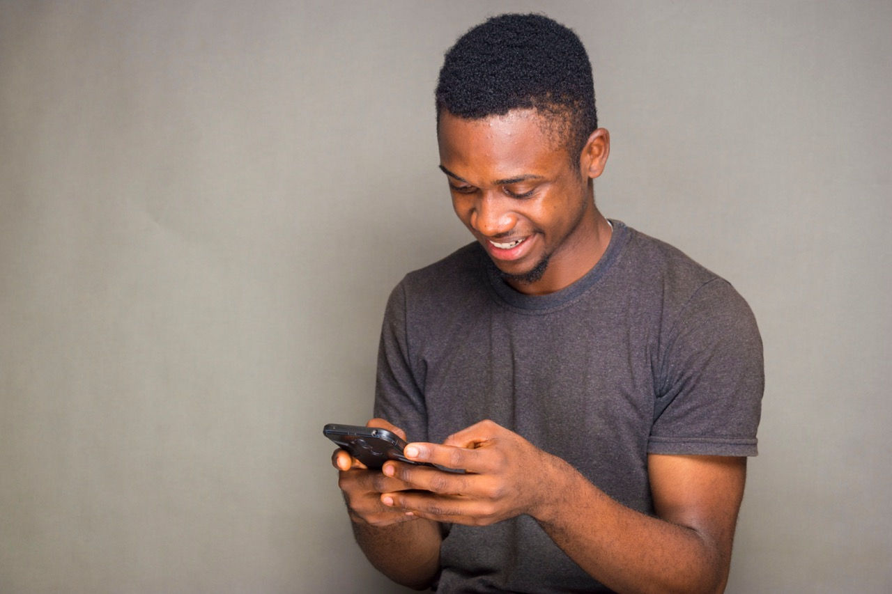 Homem consumidor segurando smartphone digitando.