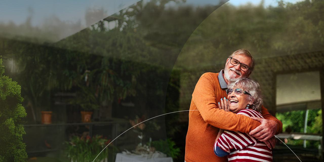 Casal de idosos feliz se abraça no quintal.