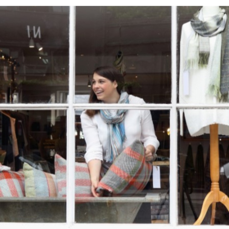 A store owners arranges pillows in the window of her store. 