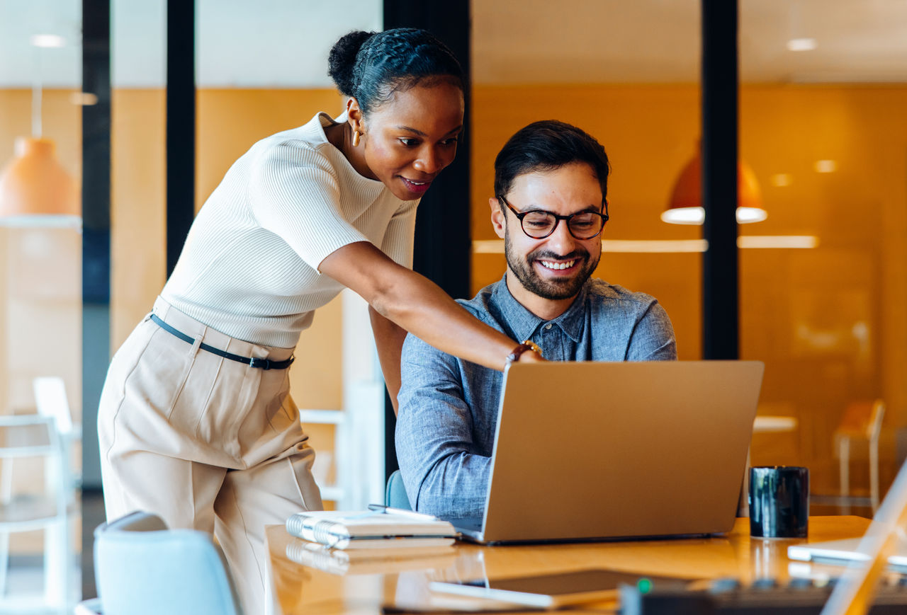 Un homme et une femme sont assis à un bureau dans un bureau, travaillant intensément sur un ordinateur portable.