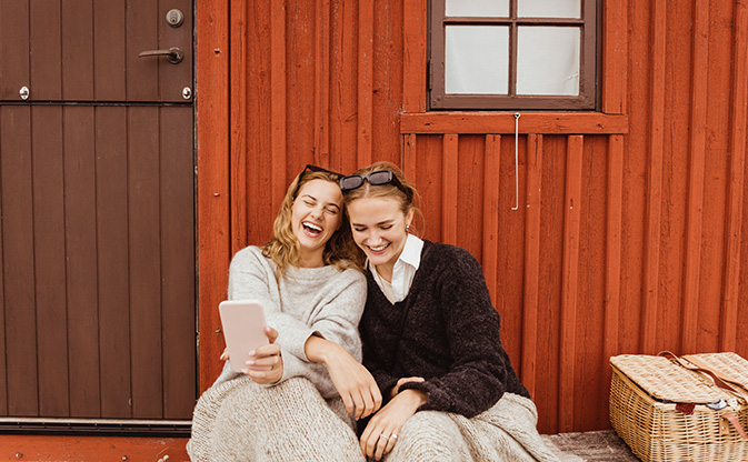 two friends looking at phone and laughing.