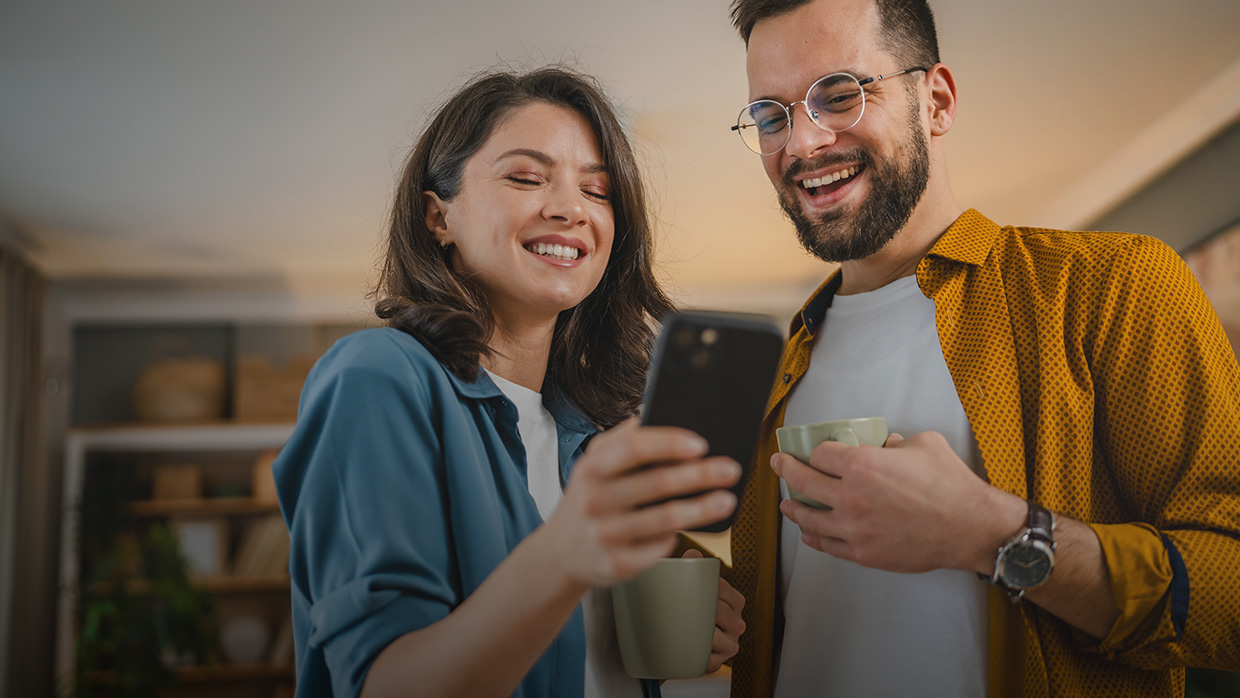 Two people looking at phone while having coffee. 