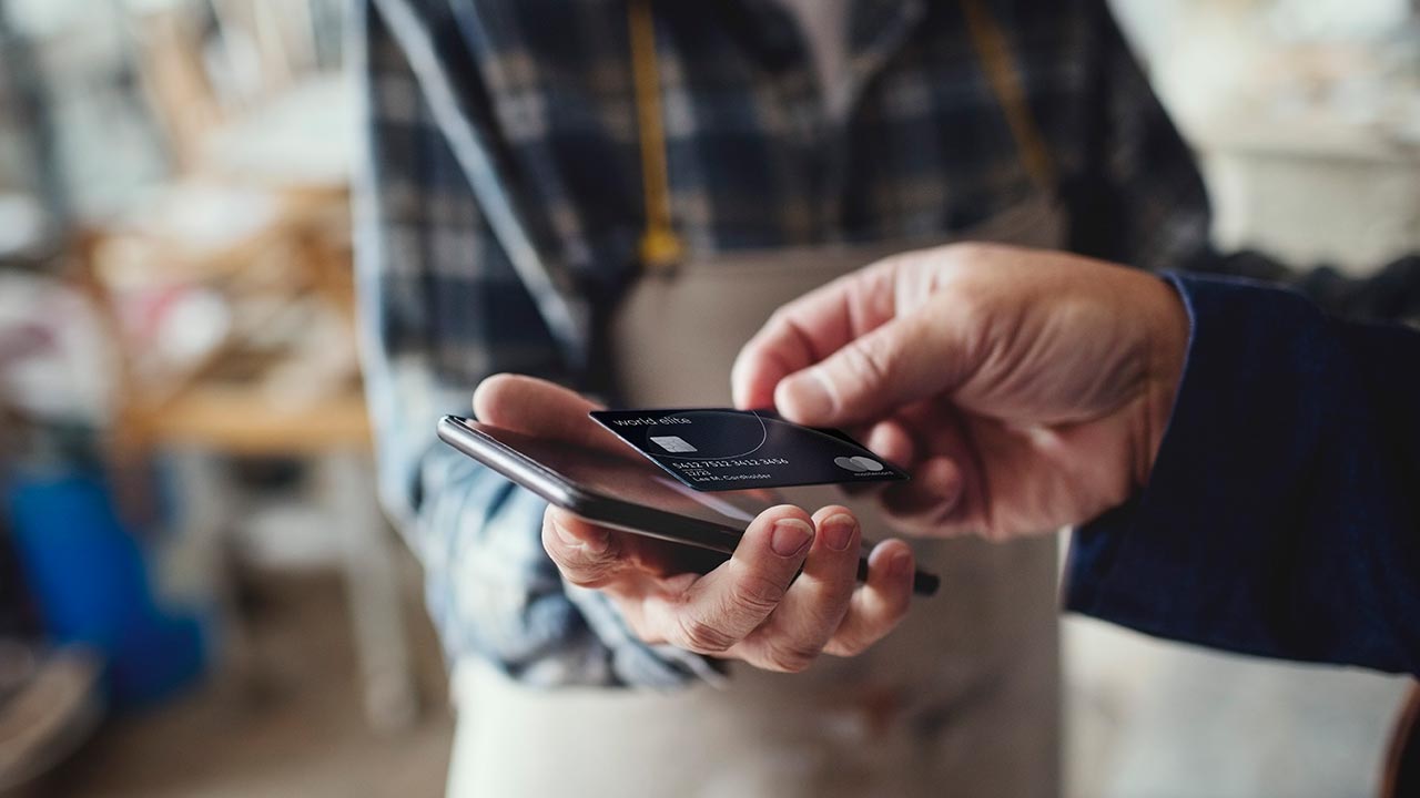 Customer making a purchase using tap on a smartphone with a credit card.