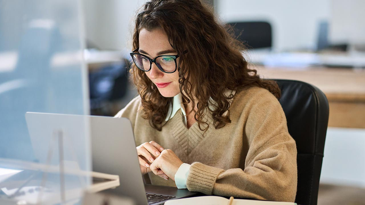 Mujer concentrada en una computadora portátil en una oficina.