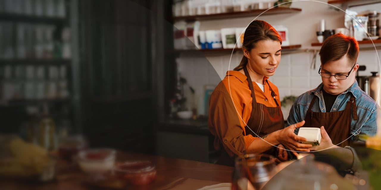 Barista enseñando a un empleado cómo usar una máquina POS.