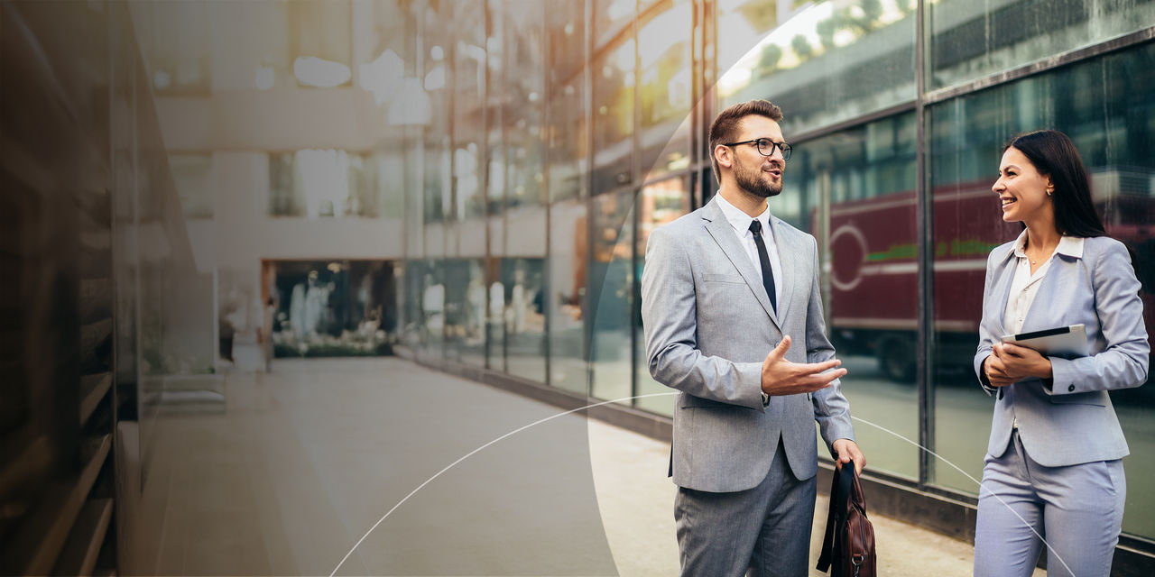 Two business professionals engaged in conversation outside a modern office building.
