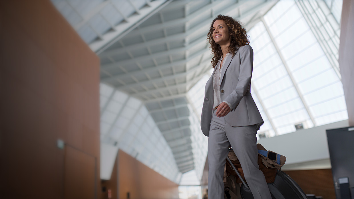 mujer de negocios sonriente arrastrando su equipaje en el aeropuerto.